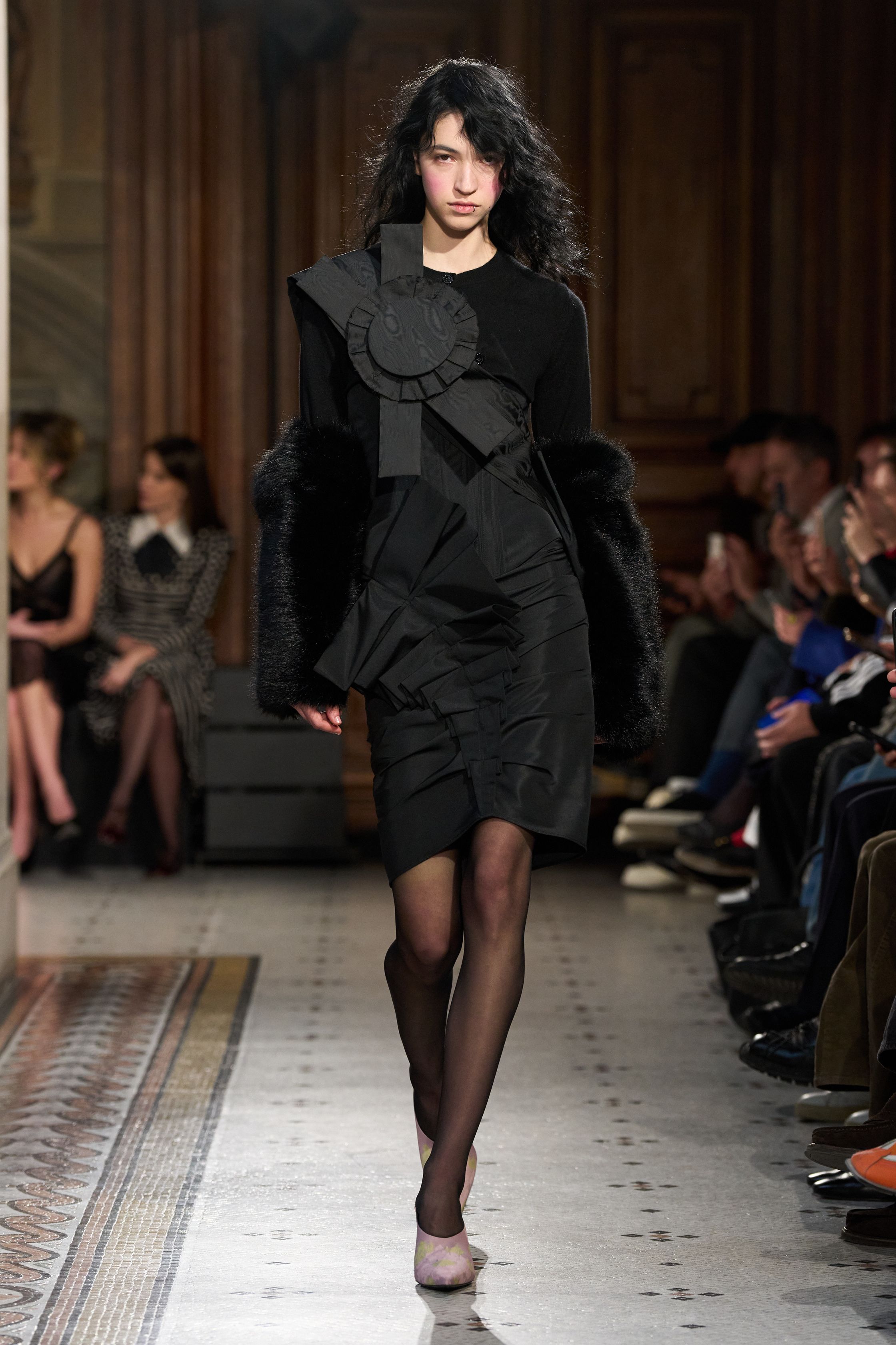 这一季 Nina Ricci 在经典巴黎优雅中加入更具戏剧张力的女性表达：黑色立体蝴蝶结装饰、豹纹雪纺长裙与结构西装形成鲜明对比，柔软与力量交织。轻薄面料与不对称层叠裙摆让整体轮廓更具流动感，既保留品牌浪漫基因，又带出一种现代女性的自信与锋芒-顽石频道趋势研究
